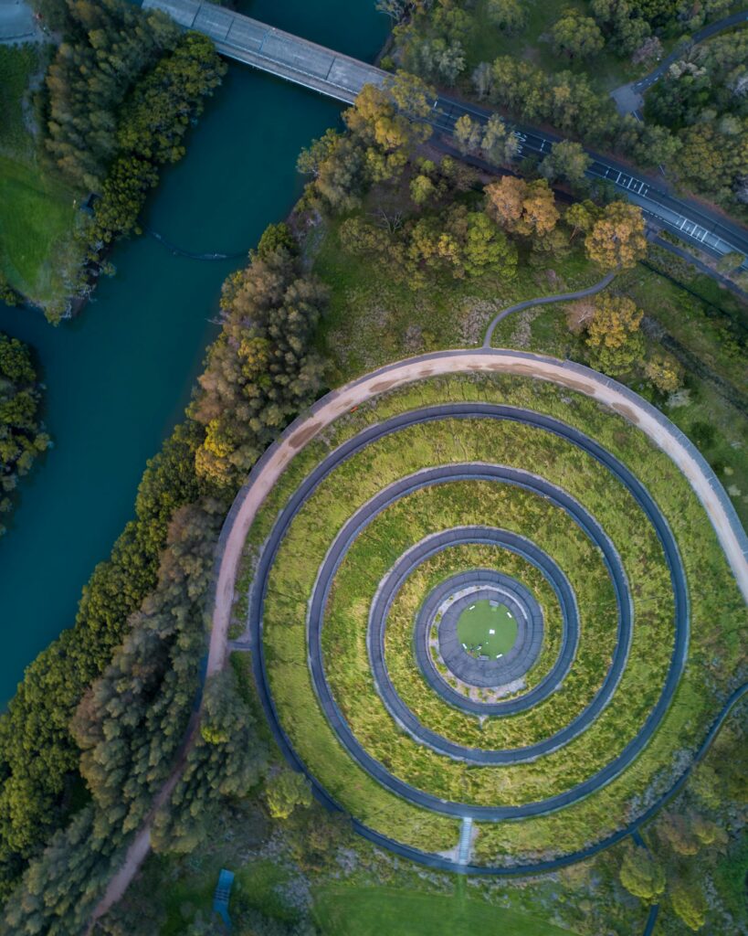 Stunning aerial view of circular garden design beside a flowing river in a lush green park.